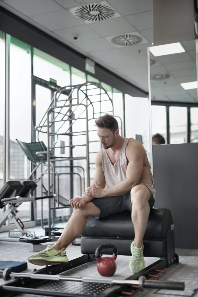 Photo by Andrea Piacquadio: https://www.pexels.com/photo/tired-male-athlete-resting-on-bench-during-weightlifting-workout-in-gym-3838706/