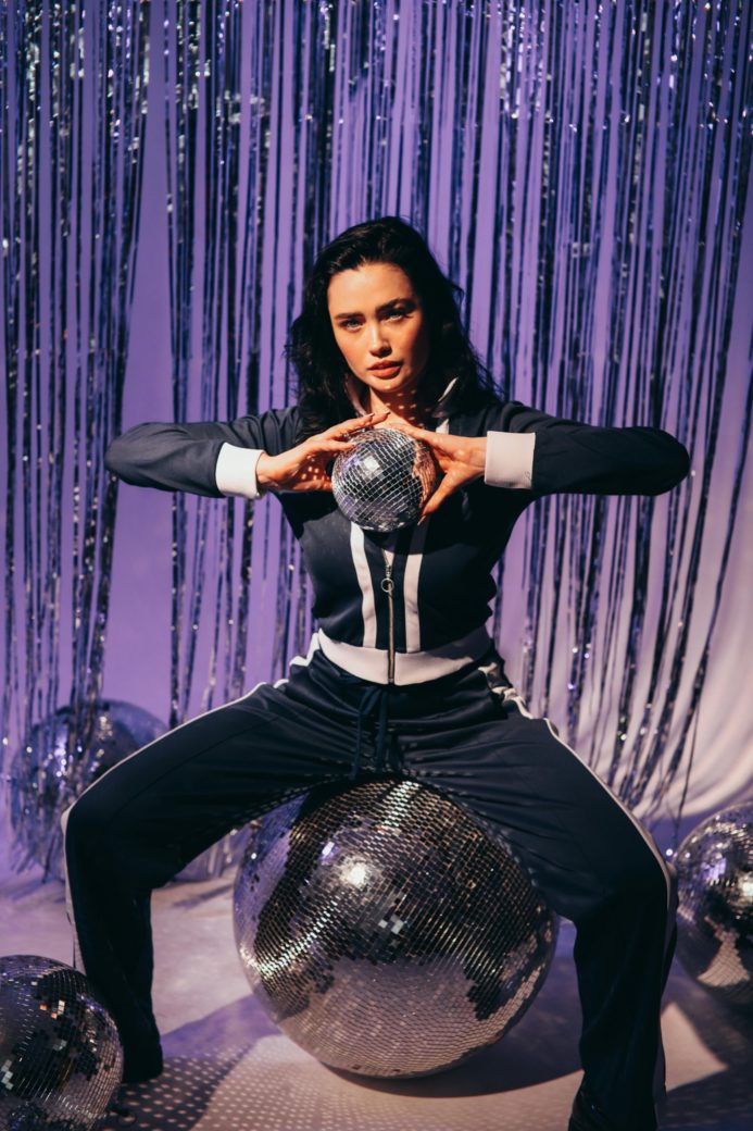 Photo by KoolShooters  : https://www.pexels.com/photo/woman-in-a-tracksuit-holding-a-disco-ball-6982559/