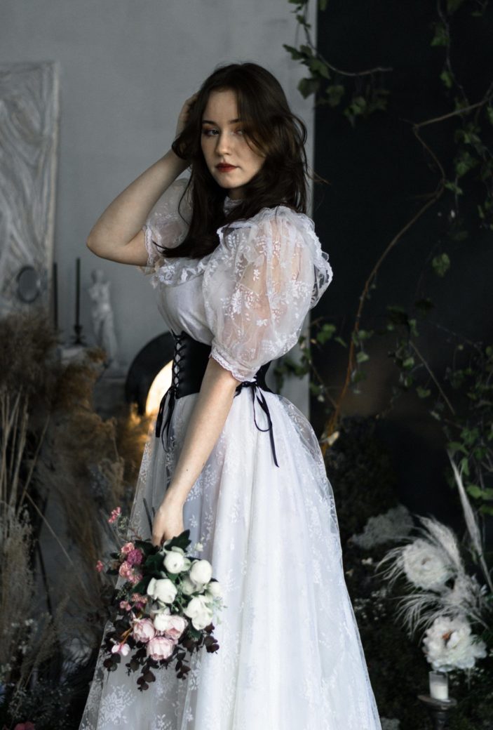 Photo by Ann Bugaichuk: https://www.pexels.com/photo/young-brunette-wearing-a-white-dress-with-a-black-corset-and-holding-a-bunch-of-flowers-16330244/