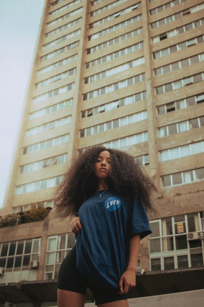 Photo by Lucas Brown: https://www.pexels.com/photo/woman-in-oversized-shirt-standing-under-skyscrapers-16314579/